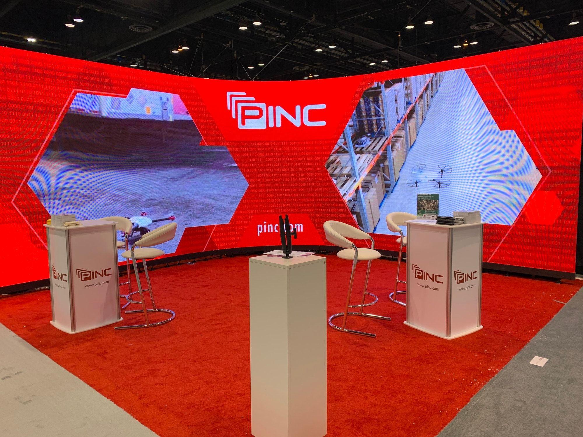 Curved LED video wall anchoring a trade show booth display