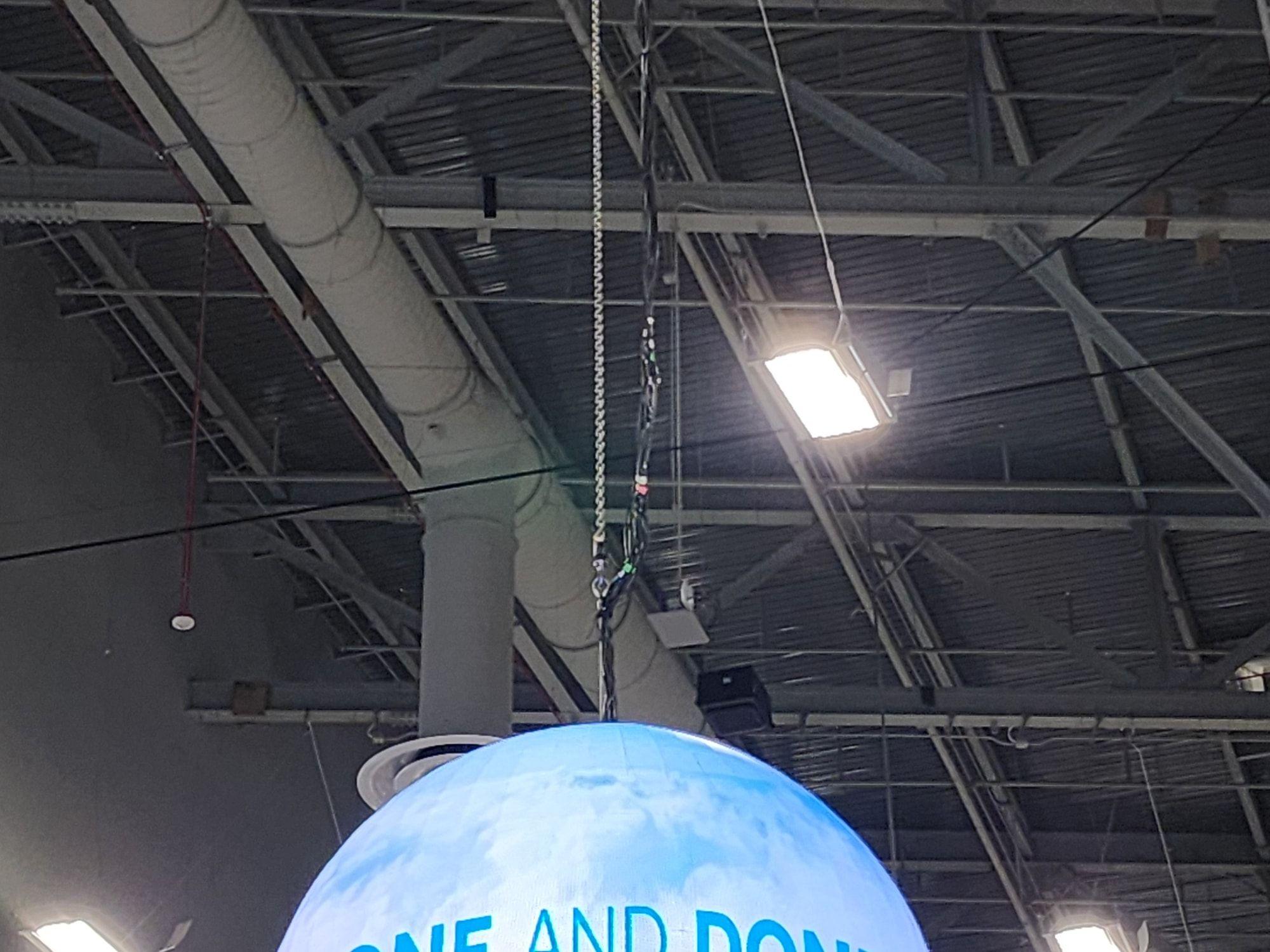 LED sphere rigged overhead inside a hangar-style trade show hall